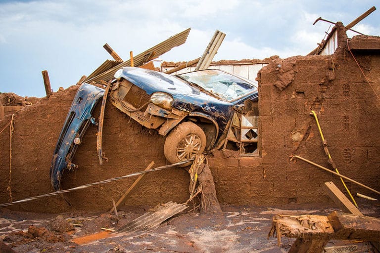 Um carro carregado pela lama atravessado em uma casa