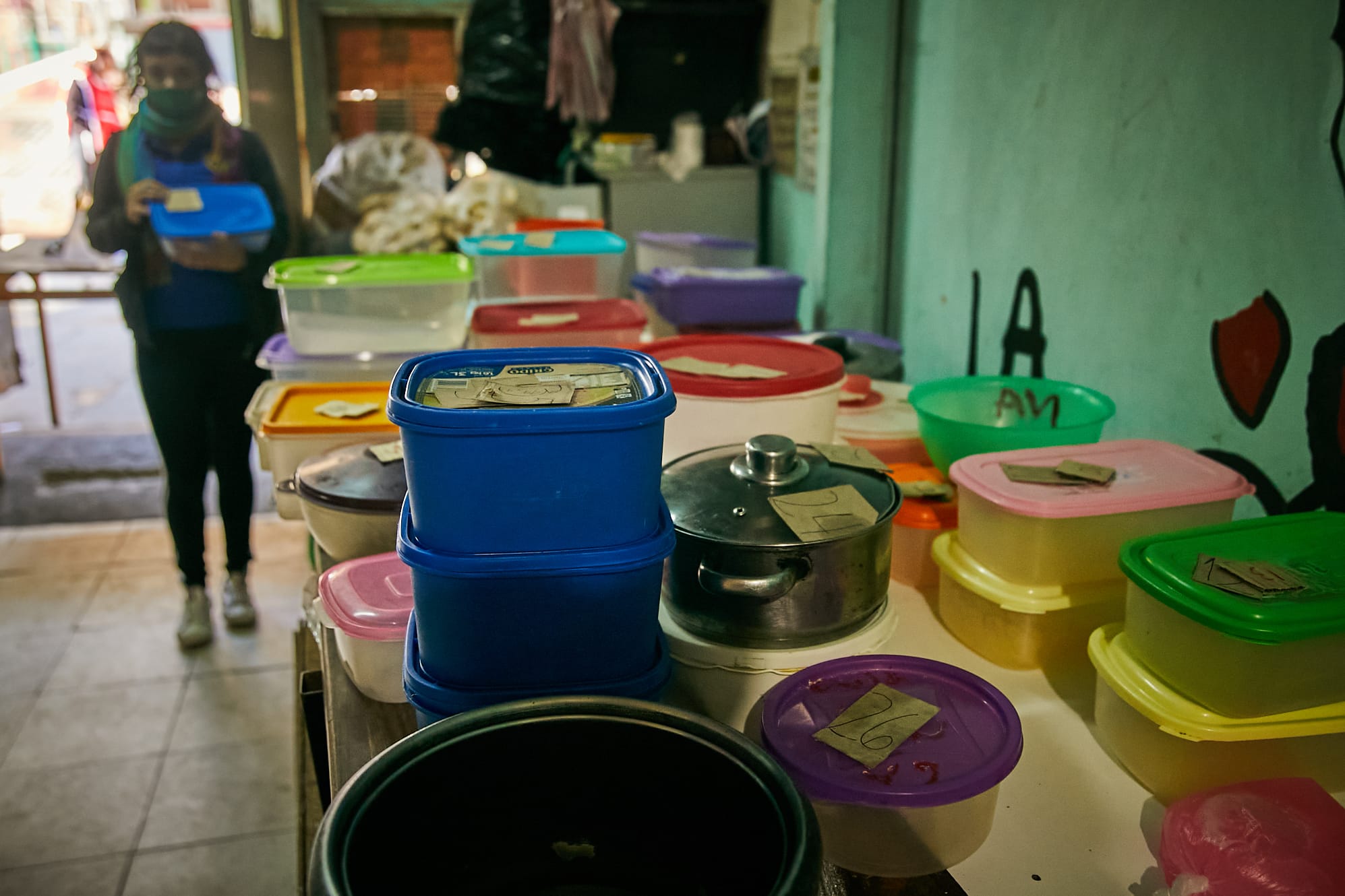 Cooks at the 'Gustavo Cortiñas' community kitchen receive daily hundreds of plastic containers they fill with food and serve at midday