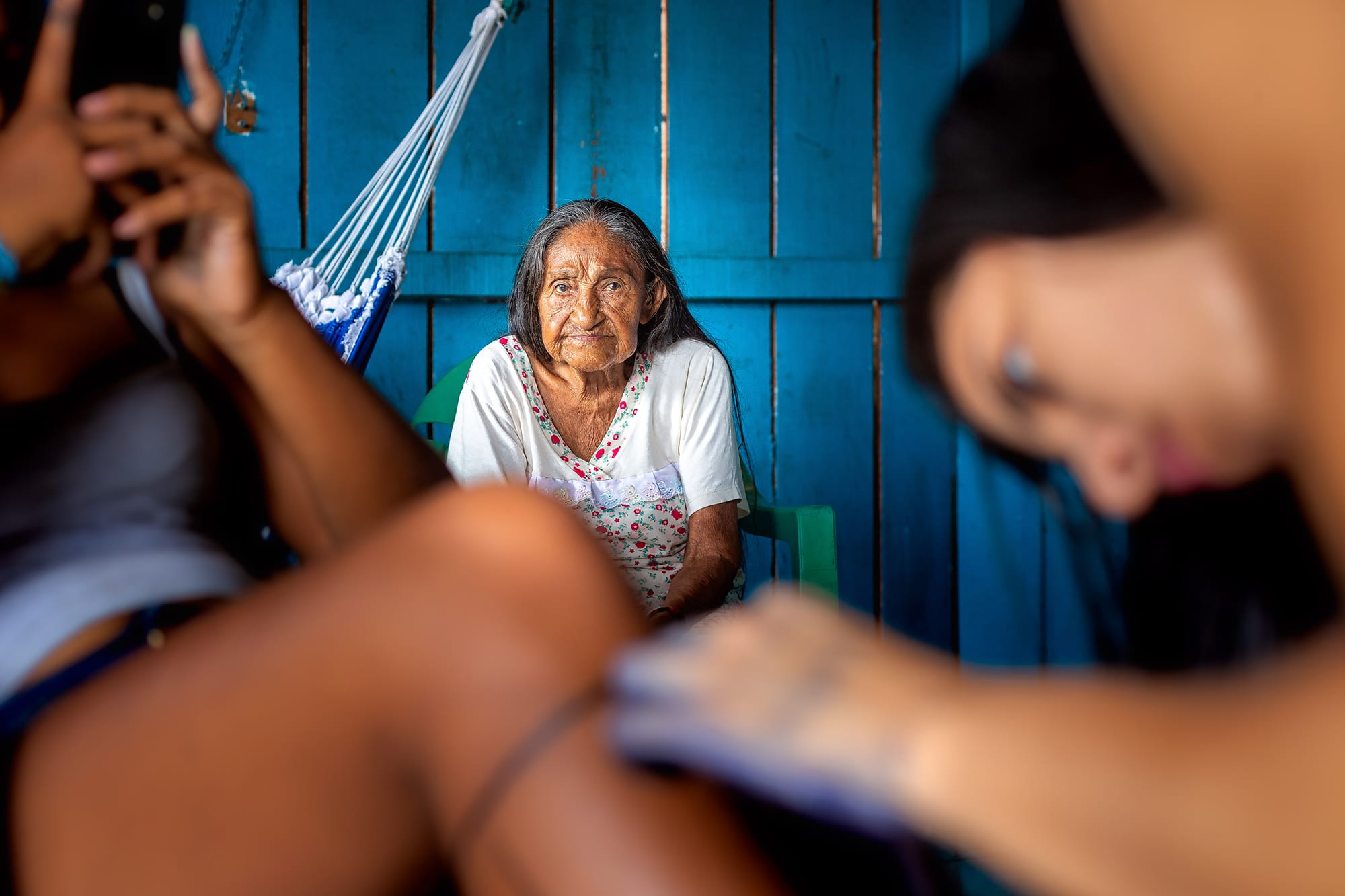 Lorena paints another girl's leg while Odete Kuruaya watches in the background