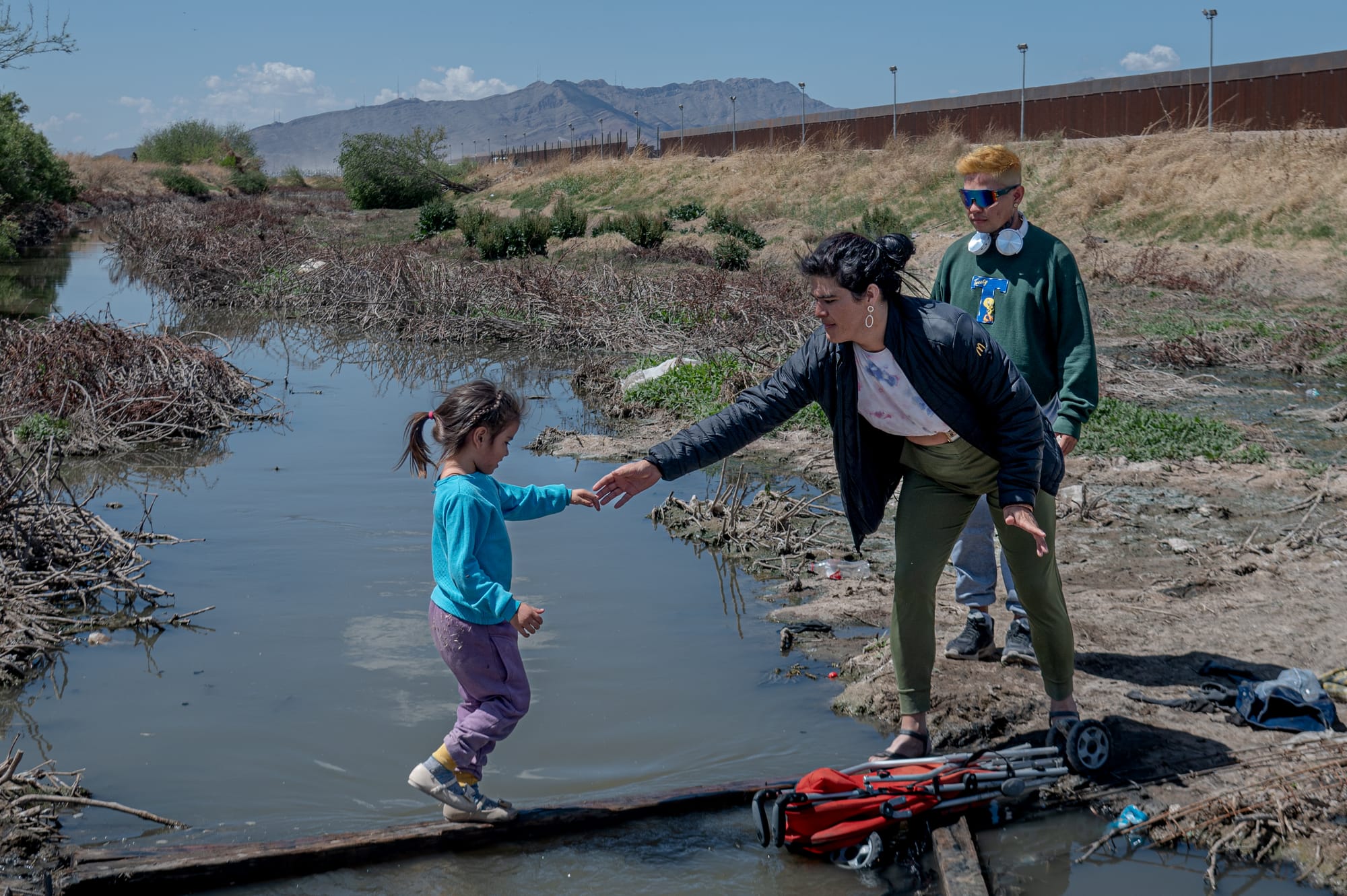 Uma mulher trans ajuda uma menina a atravessar um córrego