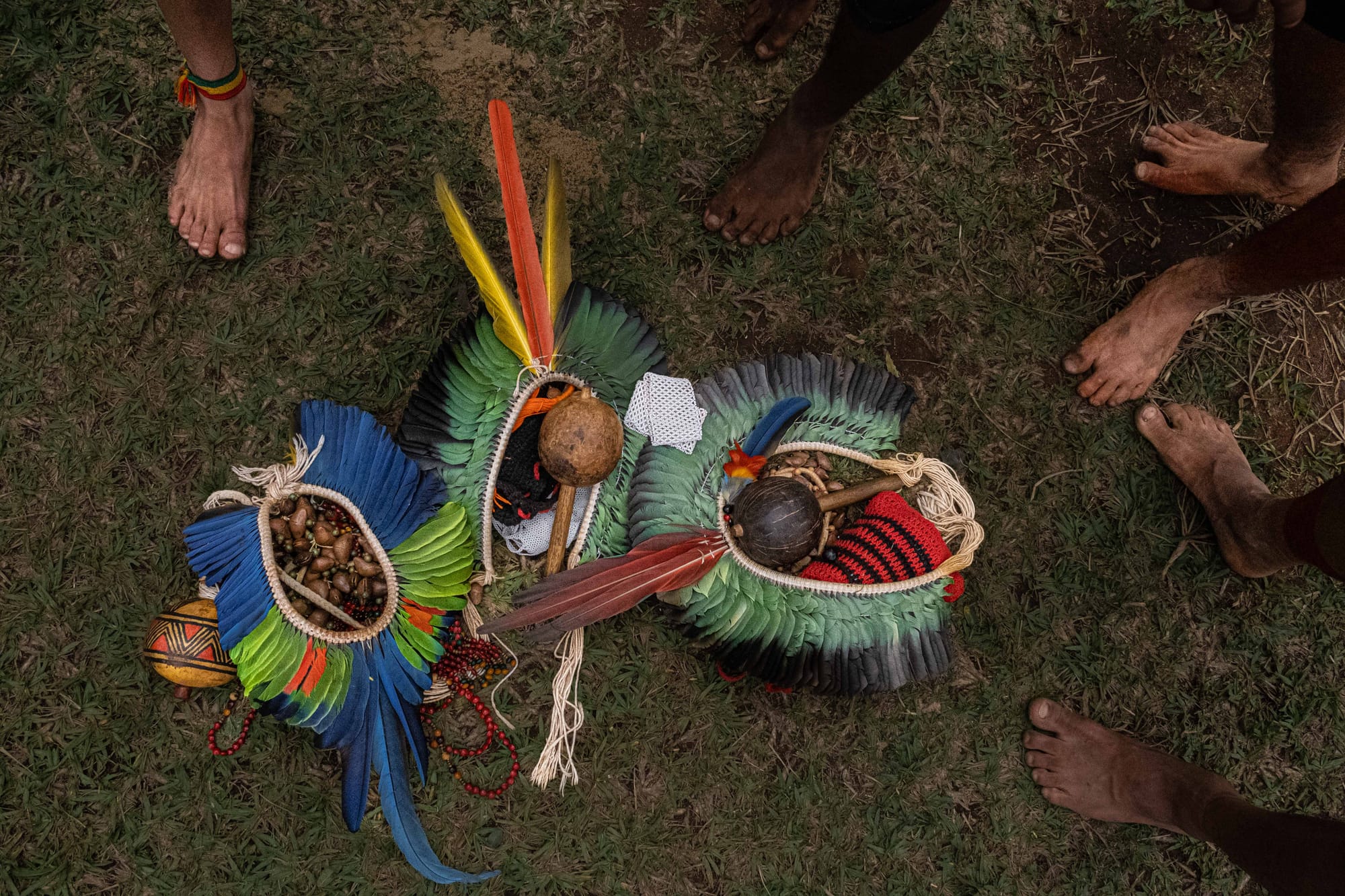 Detalhes de pés, cocar e instrumentos musicais sobre a grama