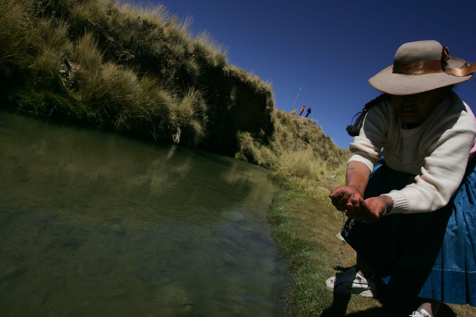 Mulher indígena pegando água com as mãos