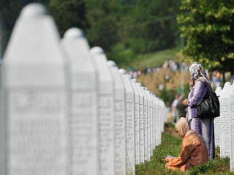 Bosnian Muslim citizens weep and pray near coffins prepared for a mass burial at the Memorial Center in Potocari, near Srebenica