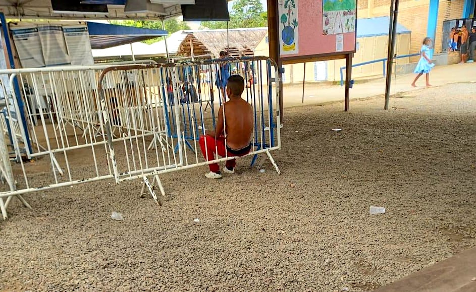 Indígena sentado em grade.