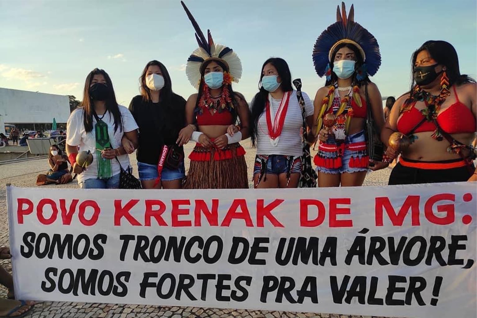 Grupo de pessoas com cartaz dizendo: 'Povo Krenak de MG: somos tronco de uma árvore, somos fortes pra valer!'