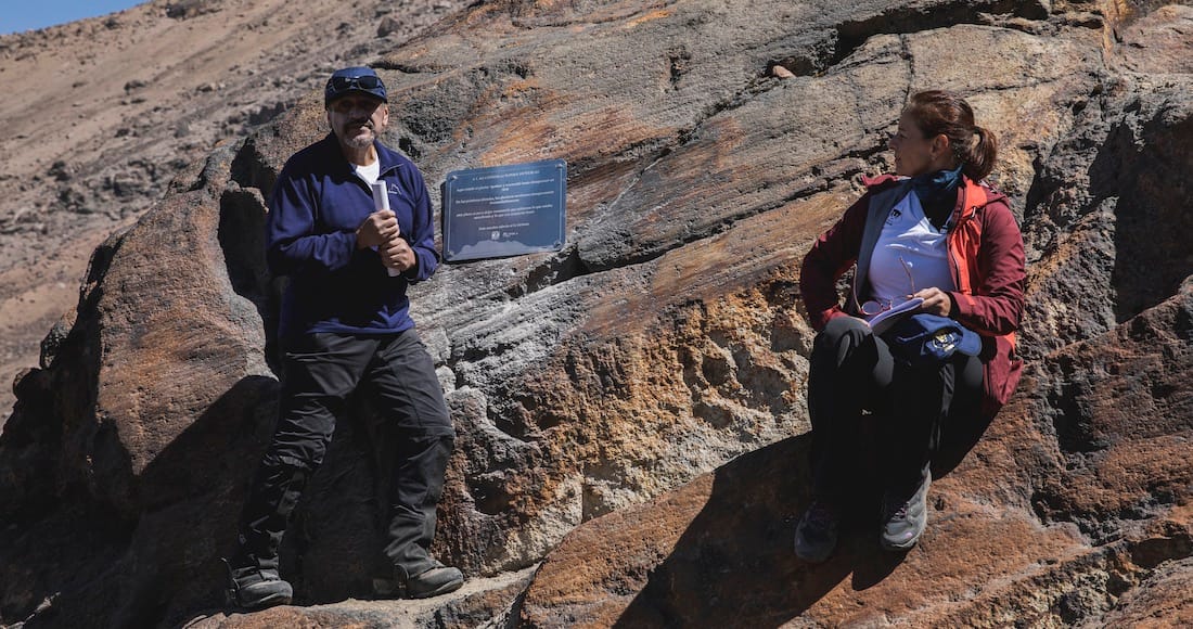 Dois pesquisadores na frente da placa
