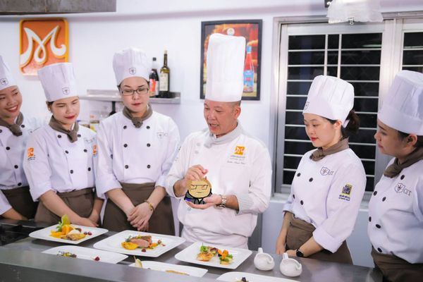 A head chef lectures a group of assistant chefs. In his hands he holds a humorous caricature of the author of this post.