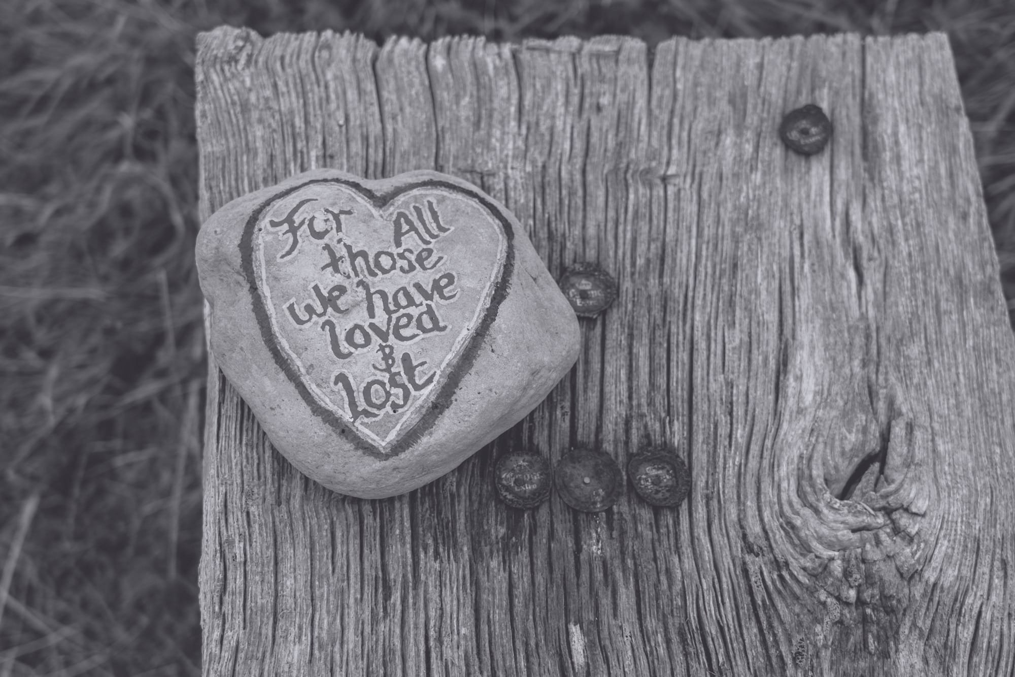 A rock with words painted on it that say "For all those we have loved and lost"