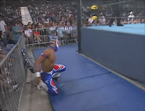 Psychosis leaps over the top rope for a dive and crashes his head into the barricade