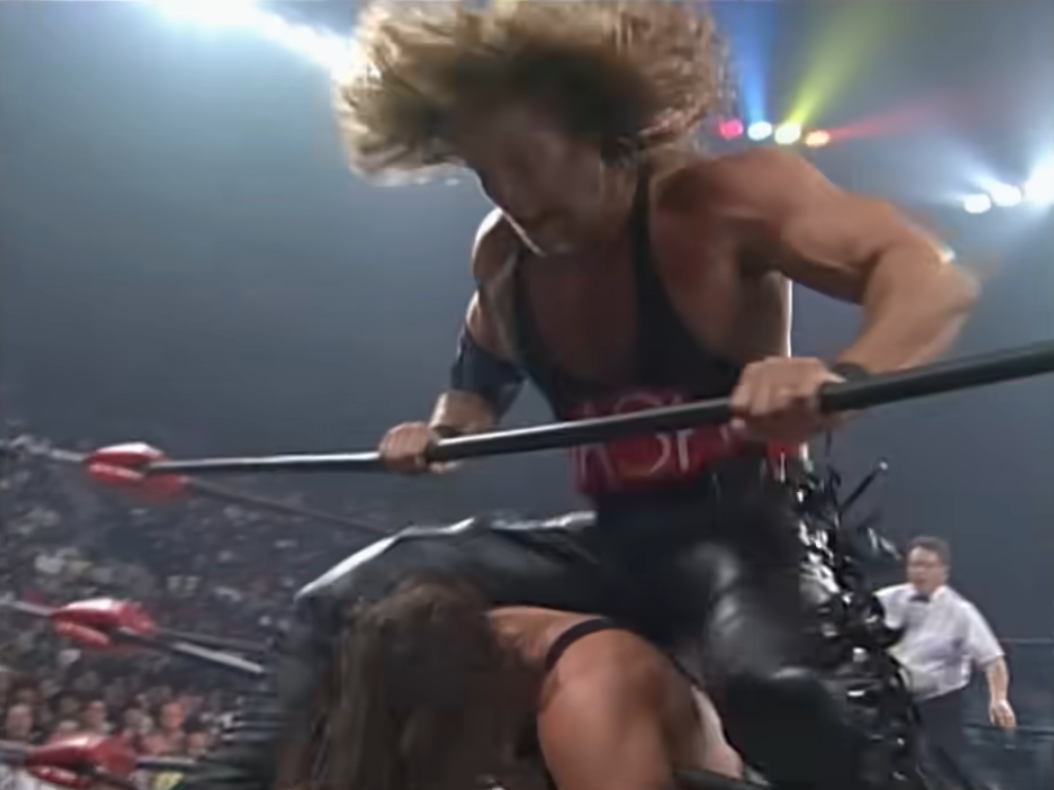 Kevin Nash hurls his taint at Sting, who is draped over the ropes by his neck.