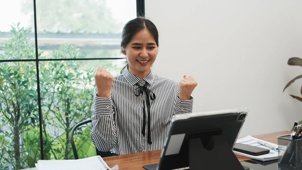 Successful investor celebrating positive financial growth on a digital tablet.