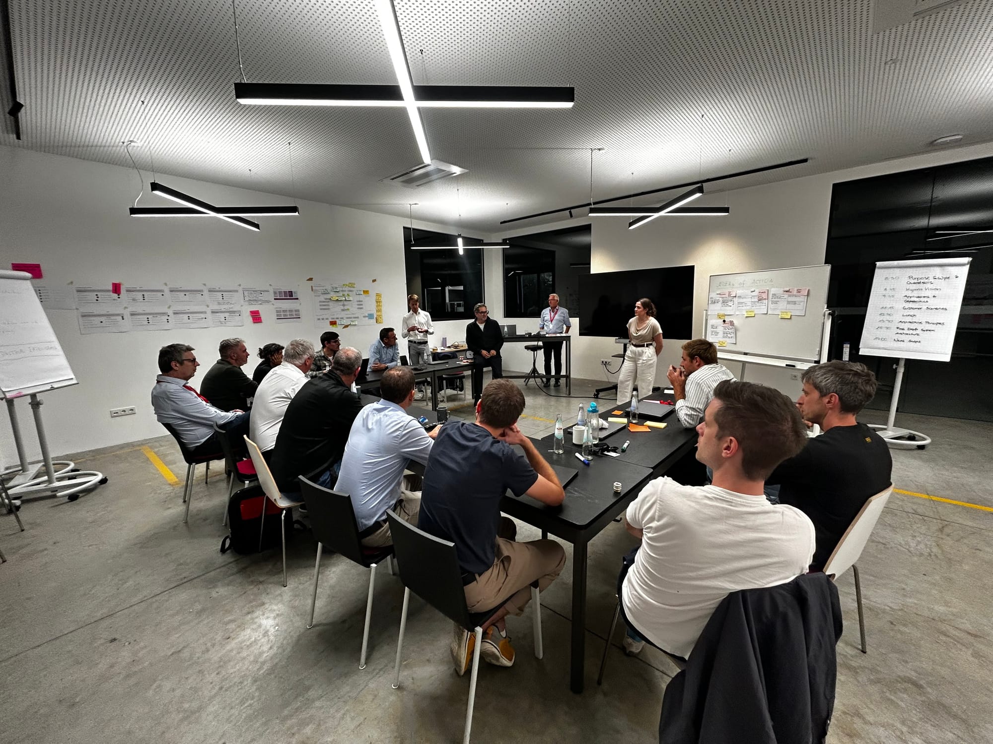 Participants seated around a long table in a meeting room in Brixen, with card walls and flip charts in the background.
