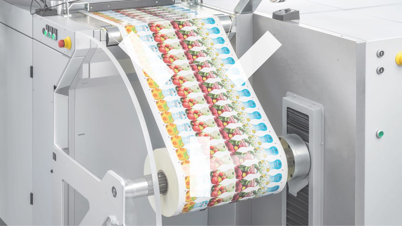A printed web with a repeating fruit and vegetable design running over the rollers of a digital press.