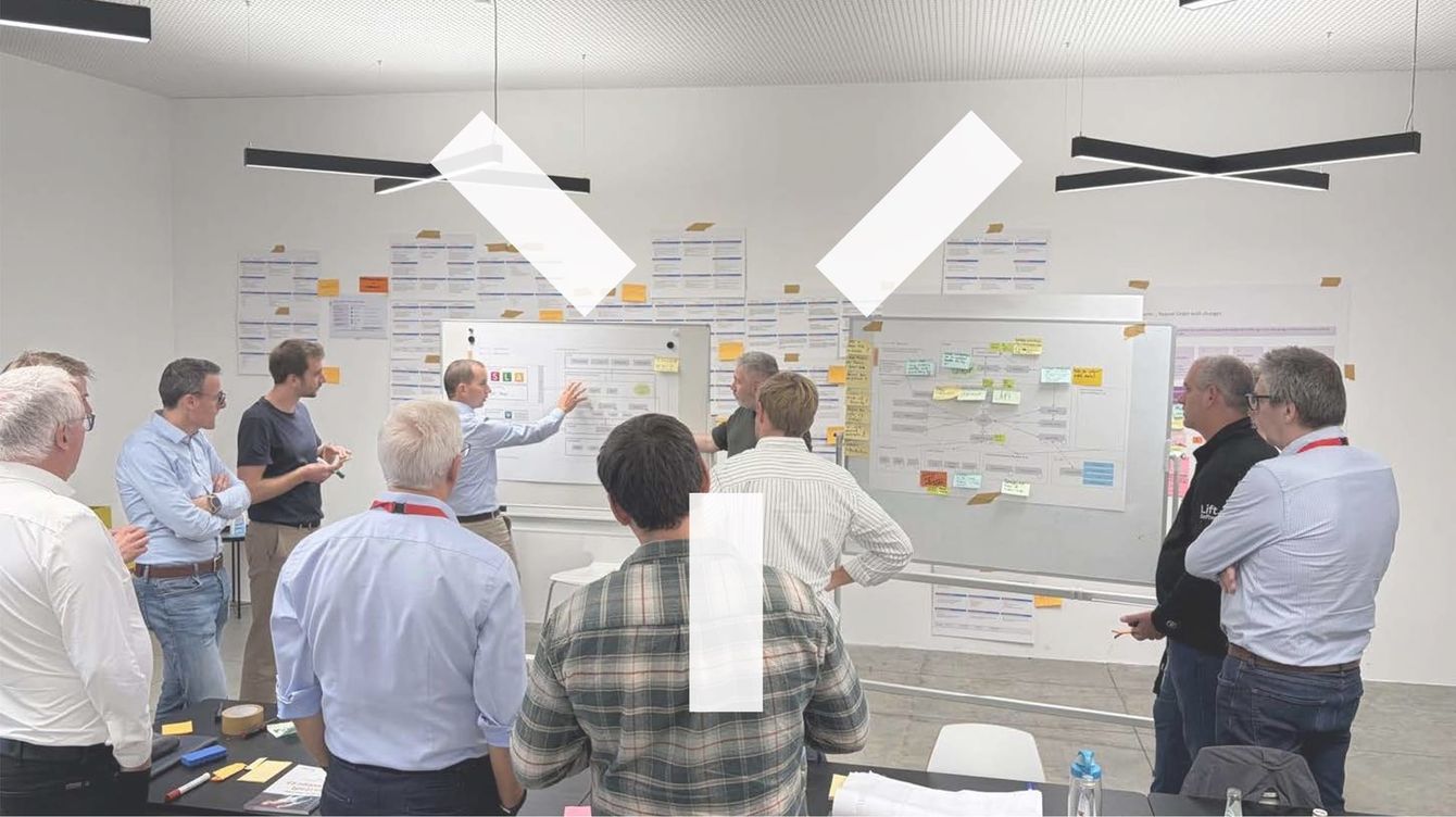 Workshop participants standing in front of a wall of colour-coded cards in a meeting room in Brixen.