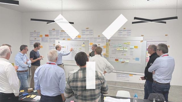 Workshop participants standing in front of a wall of colour-coded cards in a meeting room in Brixen.