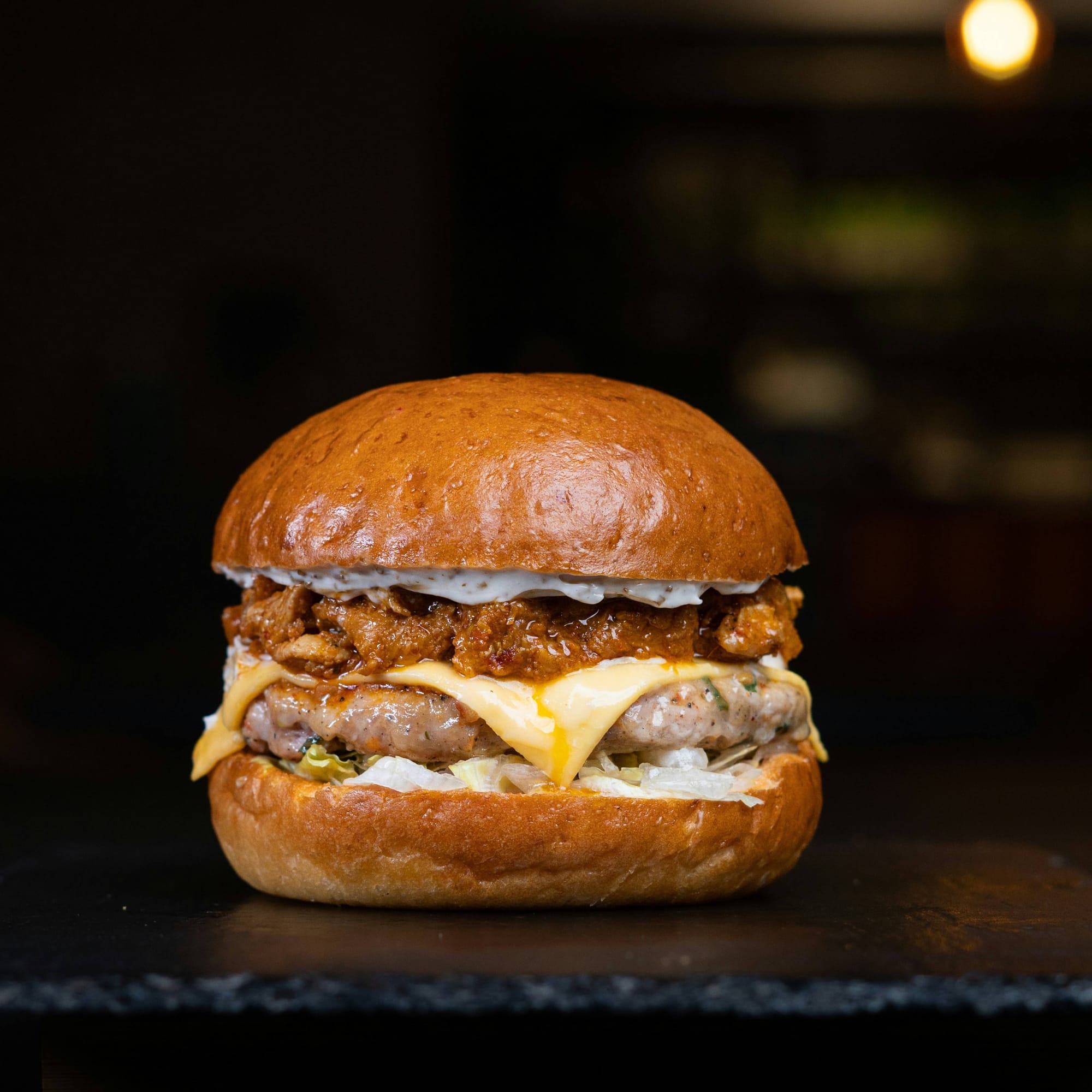 A hamburger resting on a table, photographed from the side