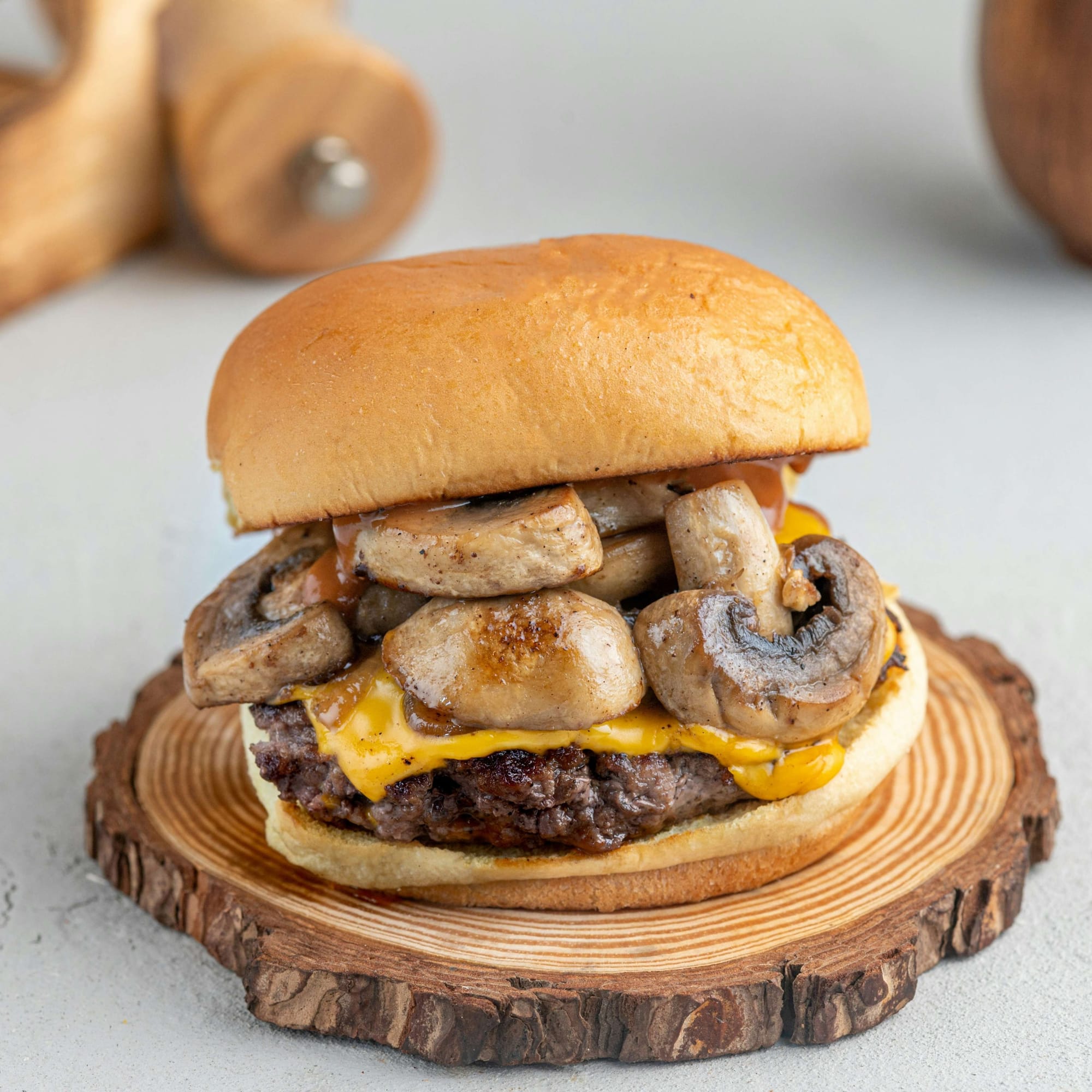 A cheeseburger topped with mushrooms, served on a wooden plate