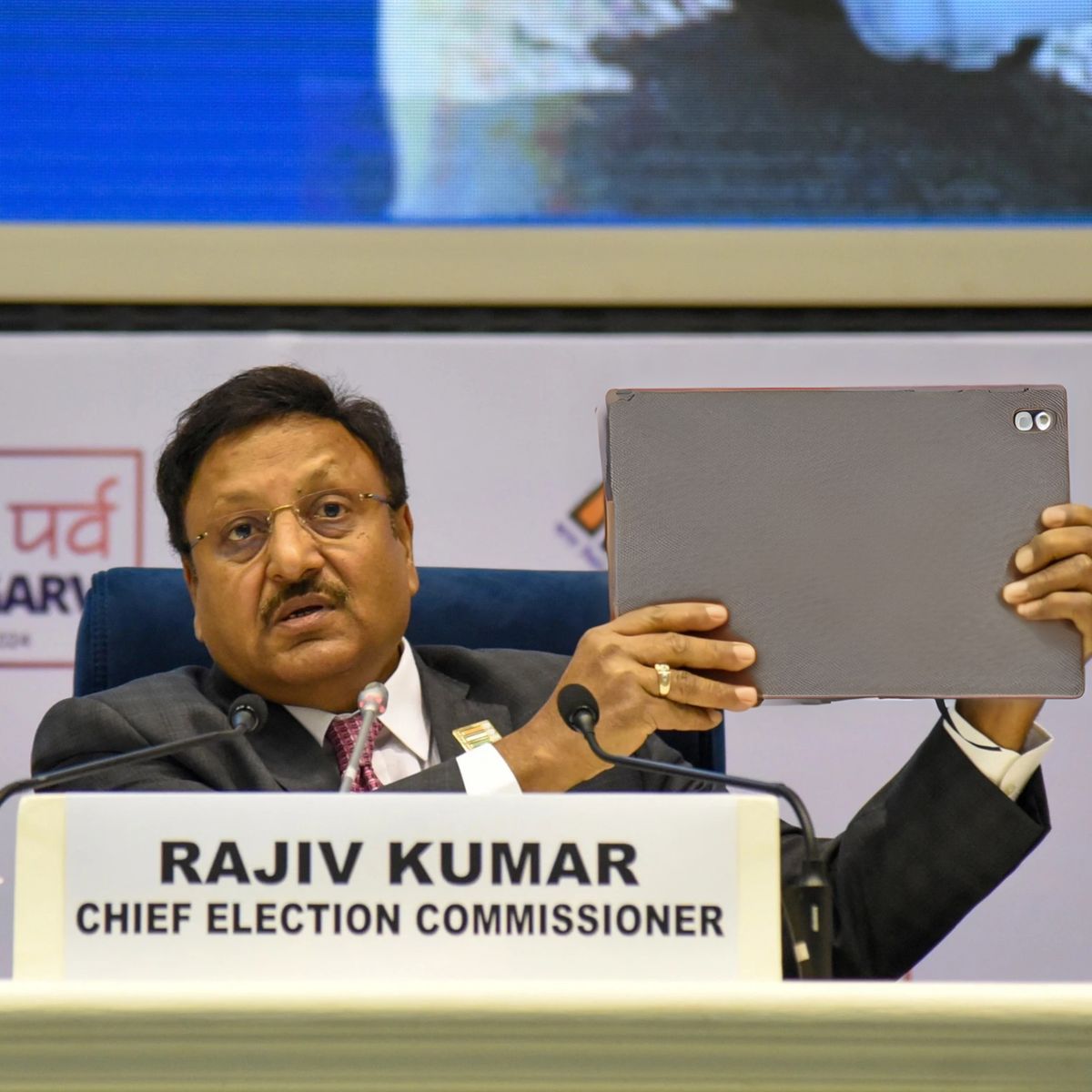 Chief Election Commissioner Rajiv Kumar holding up a tablet during press conference