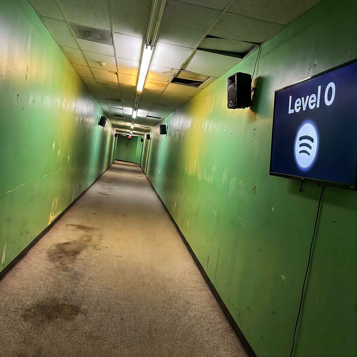 A decaying green corridor with a screen displaying "Level 0" and the Spotify logo