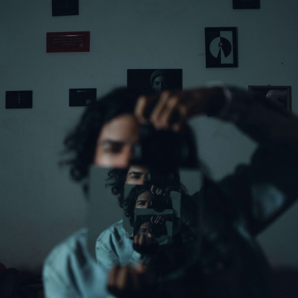 Curly-haired person holds camera to mirror as the reflection repeats into infinity