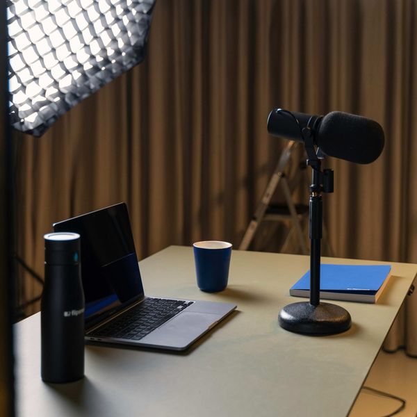 Podcast recording setup with microphone, laptop, and softbox lighting