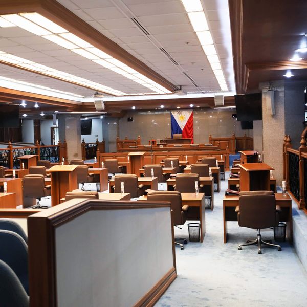 Empty Philippine Senate session hall with desks and flag at rostrum