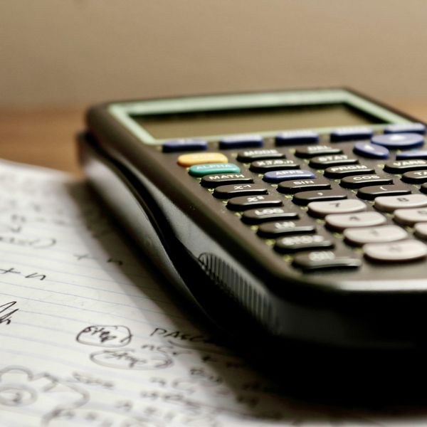 Scientific calculator resting on handwritten math notes and equations