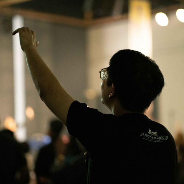 Silhouetted person raising hand at a dimly lit indoor event