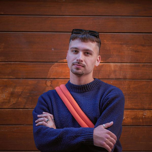 Man with arms crossed and sunglasses on head, looking satisfied