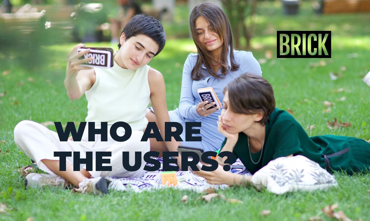 Three women sitting in a park looking at their phones