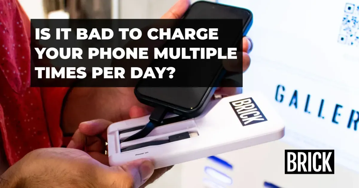 A person turning on a Brick power bank to charge their iPhone