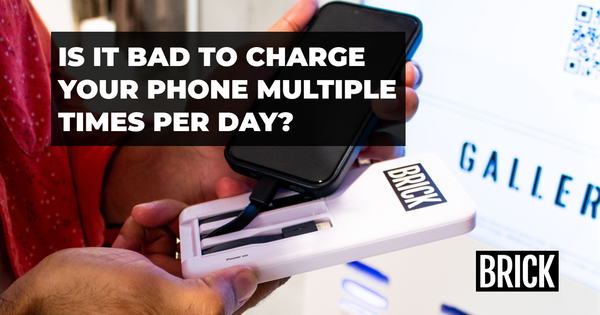 A person turning on a Brick power bank to charge their iPhone