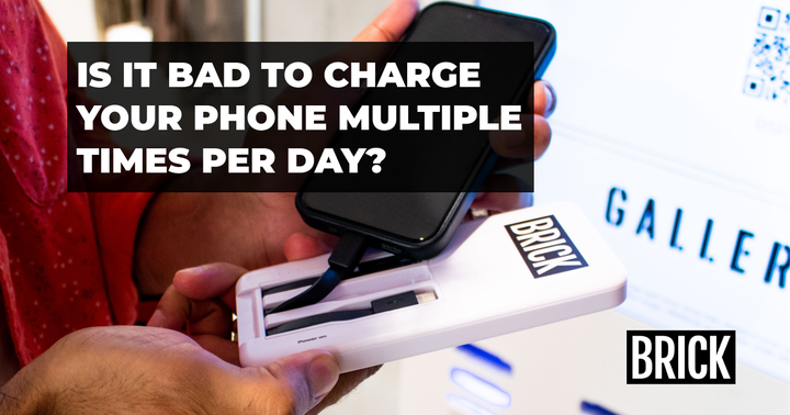 A person turning on a Brick power bank to charge their iPhone