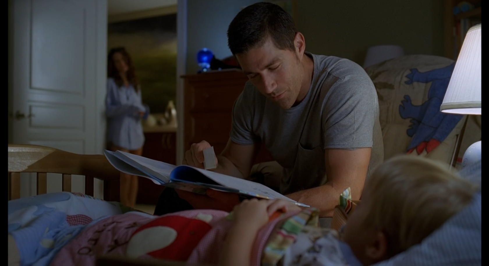 Jack Shephard reads to toddler Aaron at bedtime. Kate watches from the doorway.