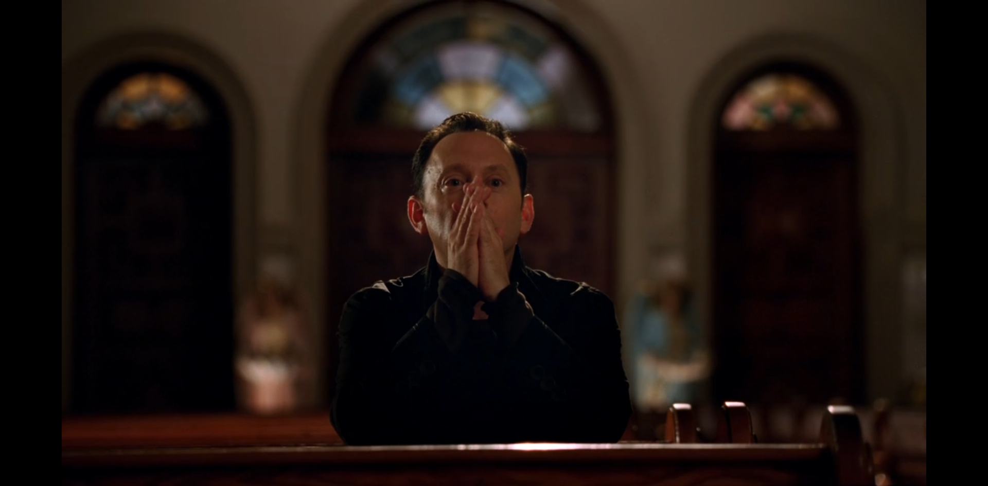 Ben Linus sits in a pew in an aspect of prayer, except for his eyes, which say "cobra about to strike."