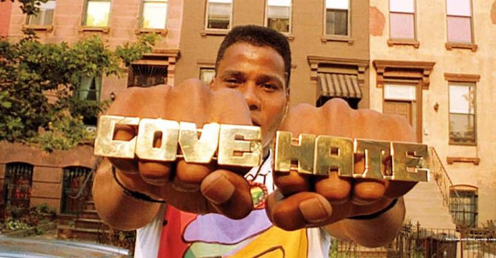 Radio Raheem (Bill Nunn) holds up brass knuckles. The right-hand says "LOVE," the left-hand says "HATE"