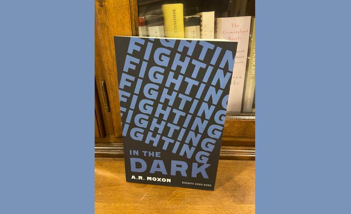 A copy of Fighting in the Dark, by A.R. Moxon, rests on a bookshelf.