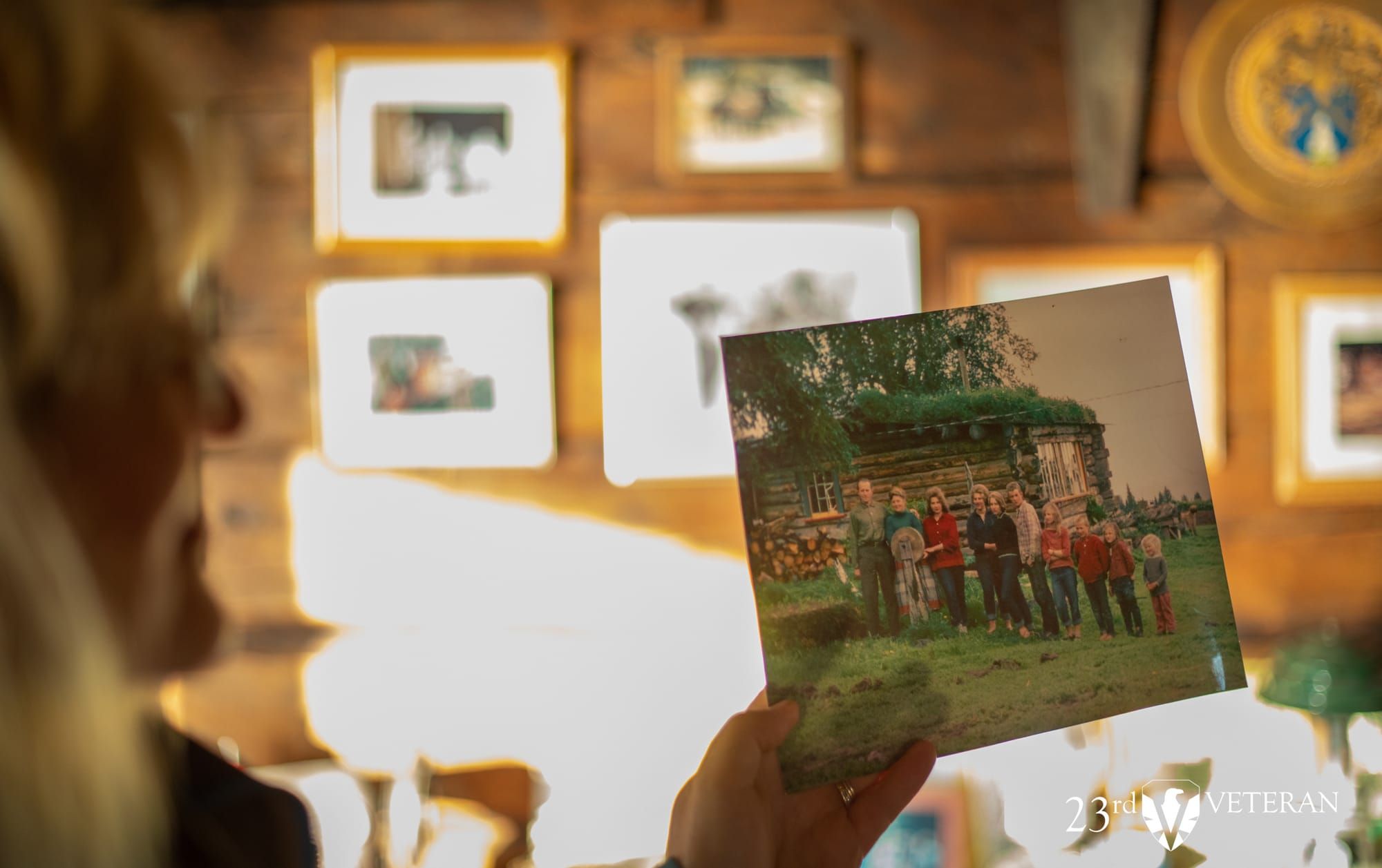 A hand holds a historic family photograph inside a homestead cabin.