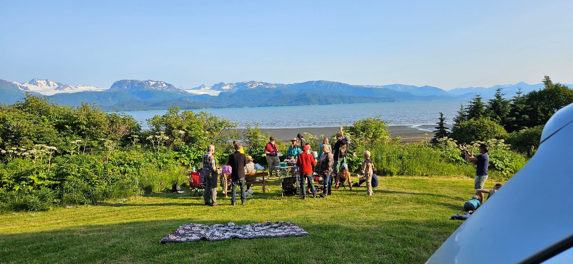 Veterans and community members gather outdoors overlooking Kachemak Bay.