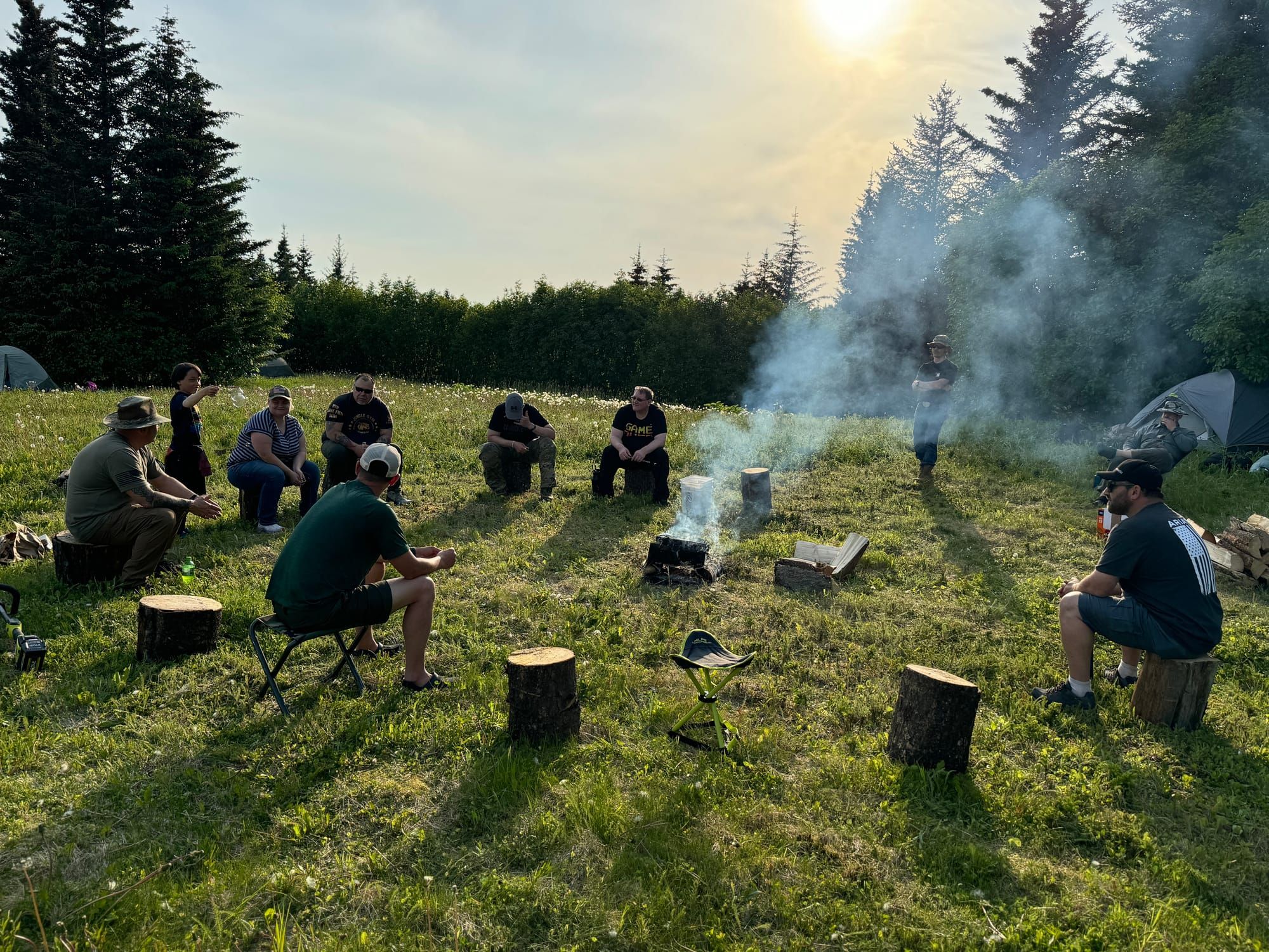 Veterans gather in a circle around a fire in an Alaska meadow.