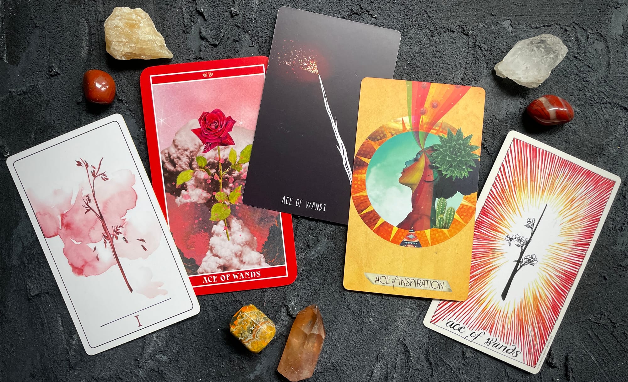 ace of wands from five decks: (left to right) the vindur deck, the goddess of love tarot, the spacious tarot, the muse tarot, and the wild unknown tarot