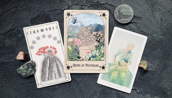 from left to right, the seven of pentacles from the lumina tarot, the every little thing you do is magic tarot, and the fountain tarot