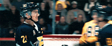 heated rivalry gif of shane & ilya: two hockey players collide in uniform, smiling, one kisses the other's helmet