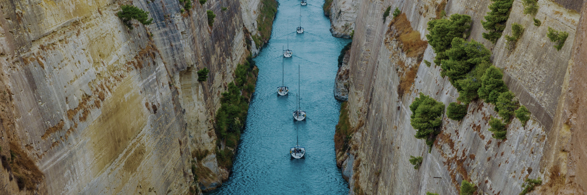 boats moving through a narrow channel of water between two rock cliffs