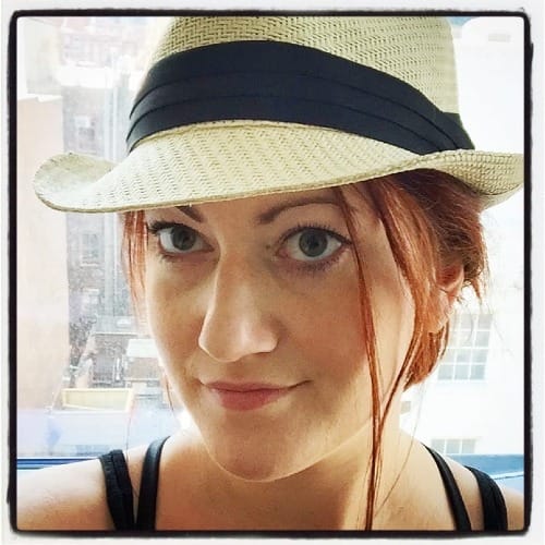 meg jones wall as a white femme in a straw-colored fedora with long red hair