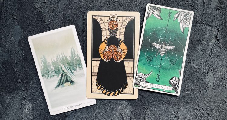 four of pentacles cards from the fountain tarot (left), fyodor pavlov tarot (center) and lumina tarot (right)