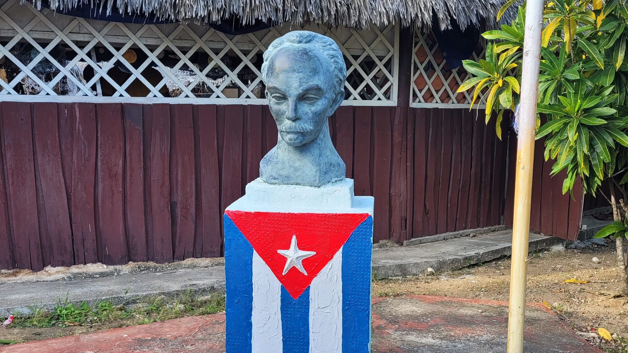A statue of Jose Marti's head ontop of a block with the Cuban flag