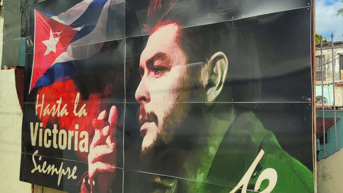 A billboard in Cuba shows a picture of Che Guevara, as the Cuban flag waves. Words read "Hasta la Victoria Siempre..." (Always forward to victory)