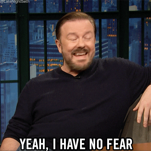 A laughing man in a dark jumper on a talk show couch, with the caption "Yeah, I have no fear".