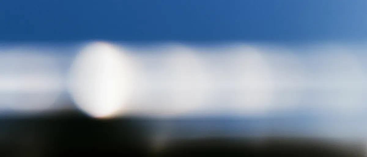blurred long exposure of the sun repeating in ghost trails across a deep blue sky above a dark horizon